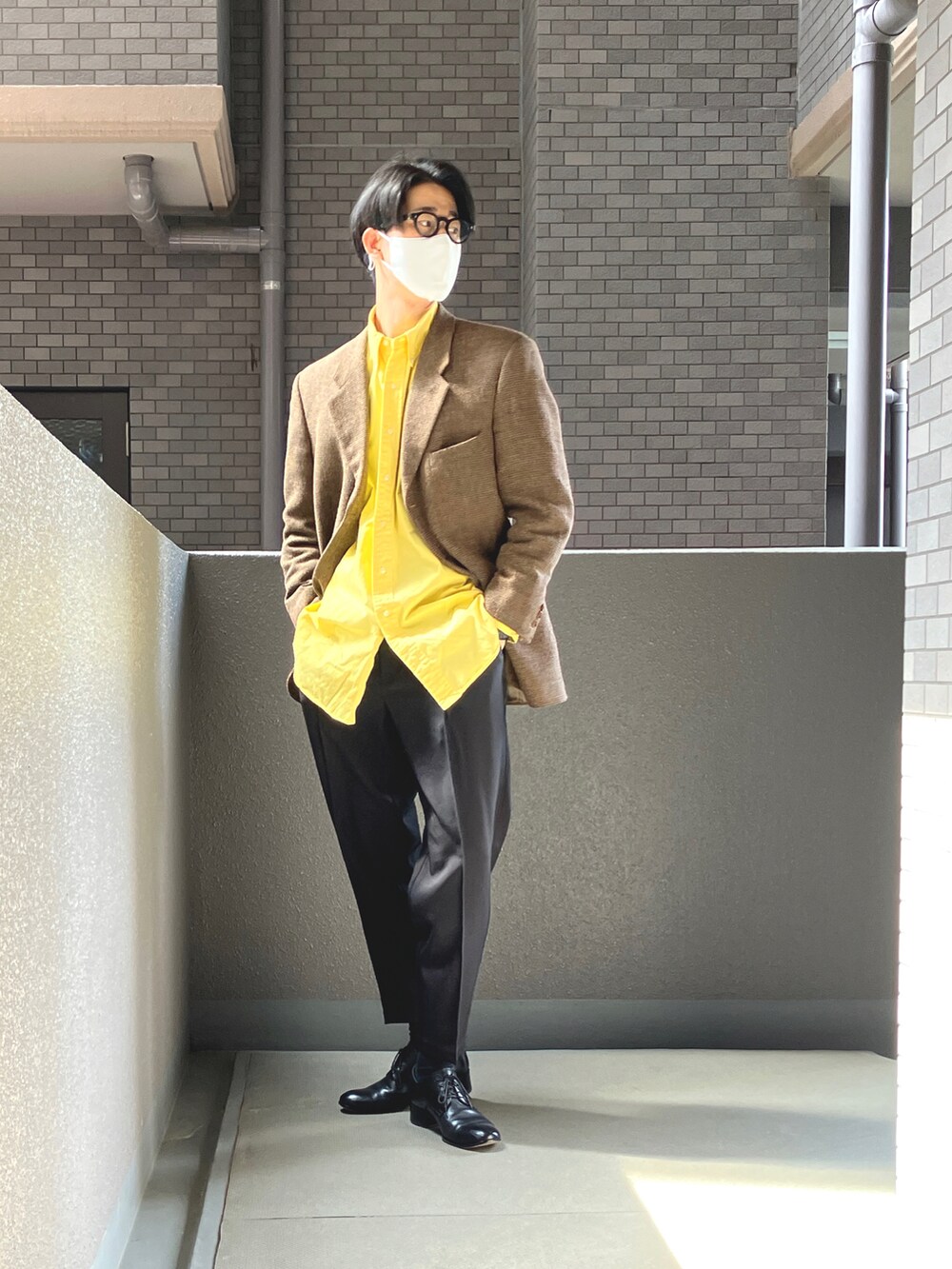 ブラック系のスラックス、ブラック系のドレスシューズ、イエロー系のシャツ/ブラウスを着用したメンズの春コーディネートの2枚目の写真