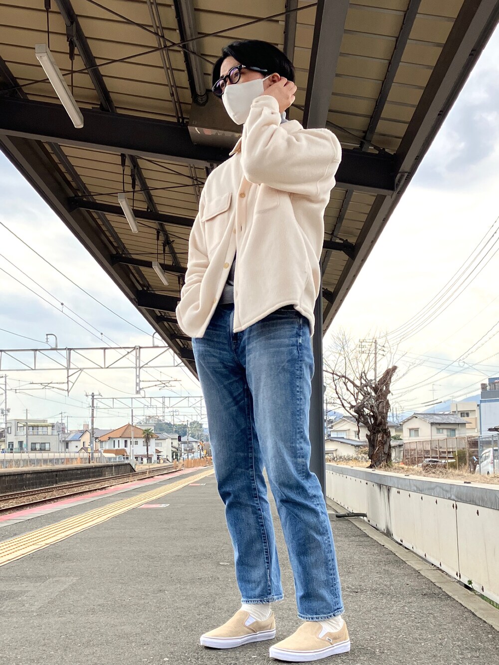 ブルー系のデニムパンツ、ベージュ系のスリッポン、ホワイト系のシャツ/ブラウスを着用したメンズの春コーディネートの2枚目の写真