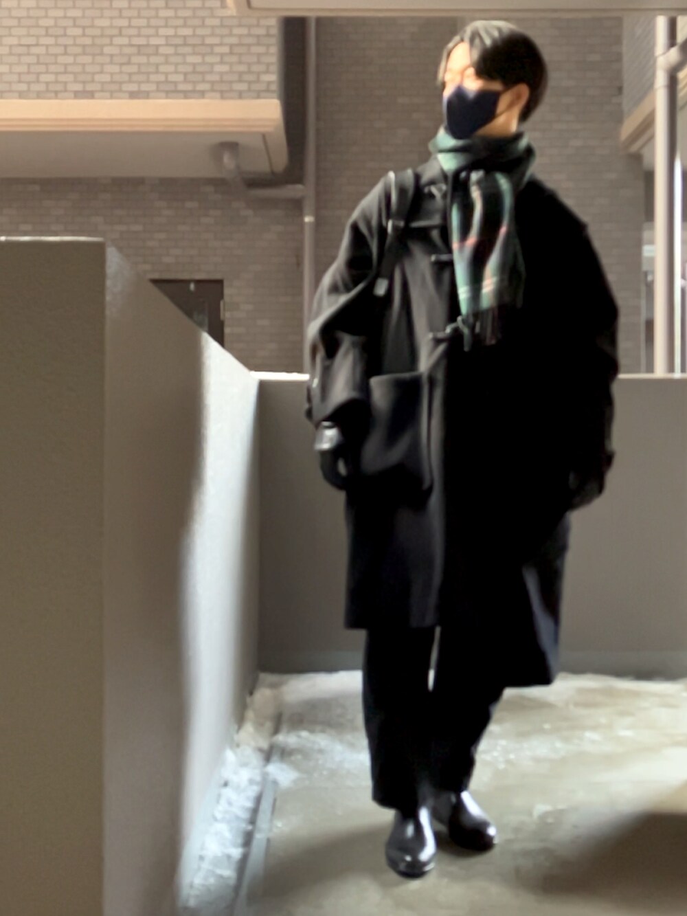 ブラック系のダッフルコート、ブラック系のその他パンツ、ブラック系のレインシューズを着用したメンズの冬コーディネートの3枚目の写真