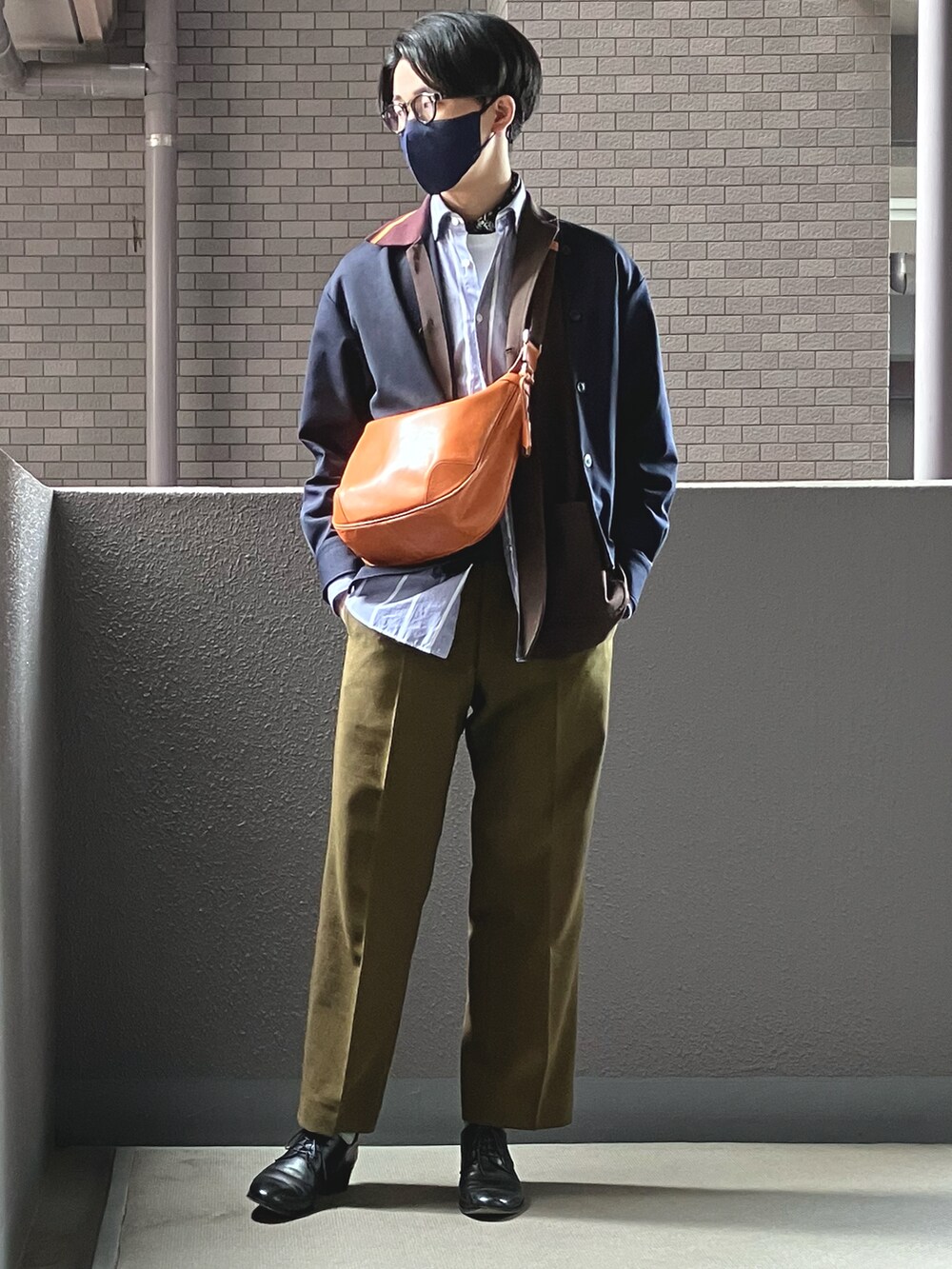 イエロー系のショルダーバッグ、グリーン系のその他パンツ、ブラック系のドレスシューズを着用したメンズの春コーディネートの2枚目の写真