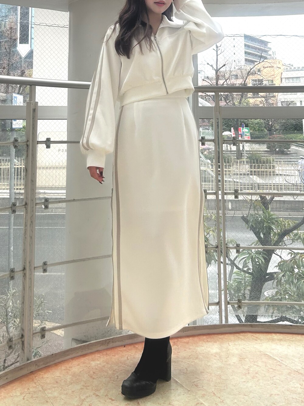 ホワイト系のその他アウター、ホワイト系のスカート、ブラック系のブーツを着用したレディースの春コーディネートの2枚目の写真