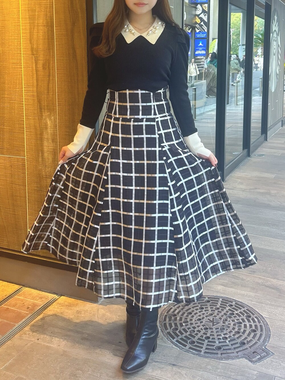 ブラック系のスカート、その他のニット/セーター、ブラック系のブーツを着用したレディースの冬コーディネートの2枚目の写真