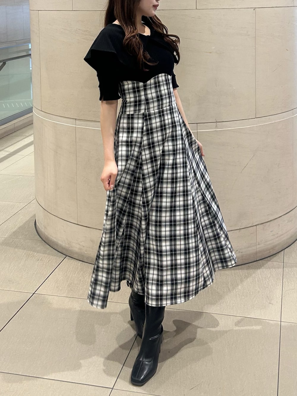 ブラック系のワンピース、ブラック系のブーツを着用したレディースの春コーディネートの2枚目の写真