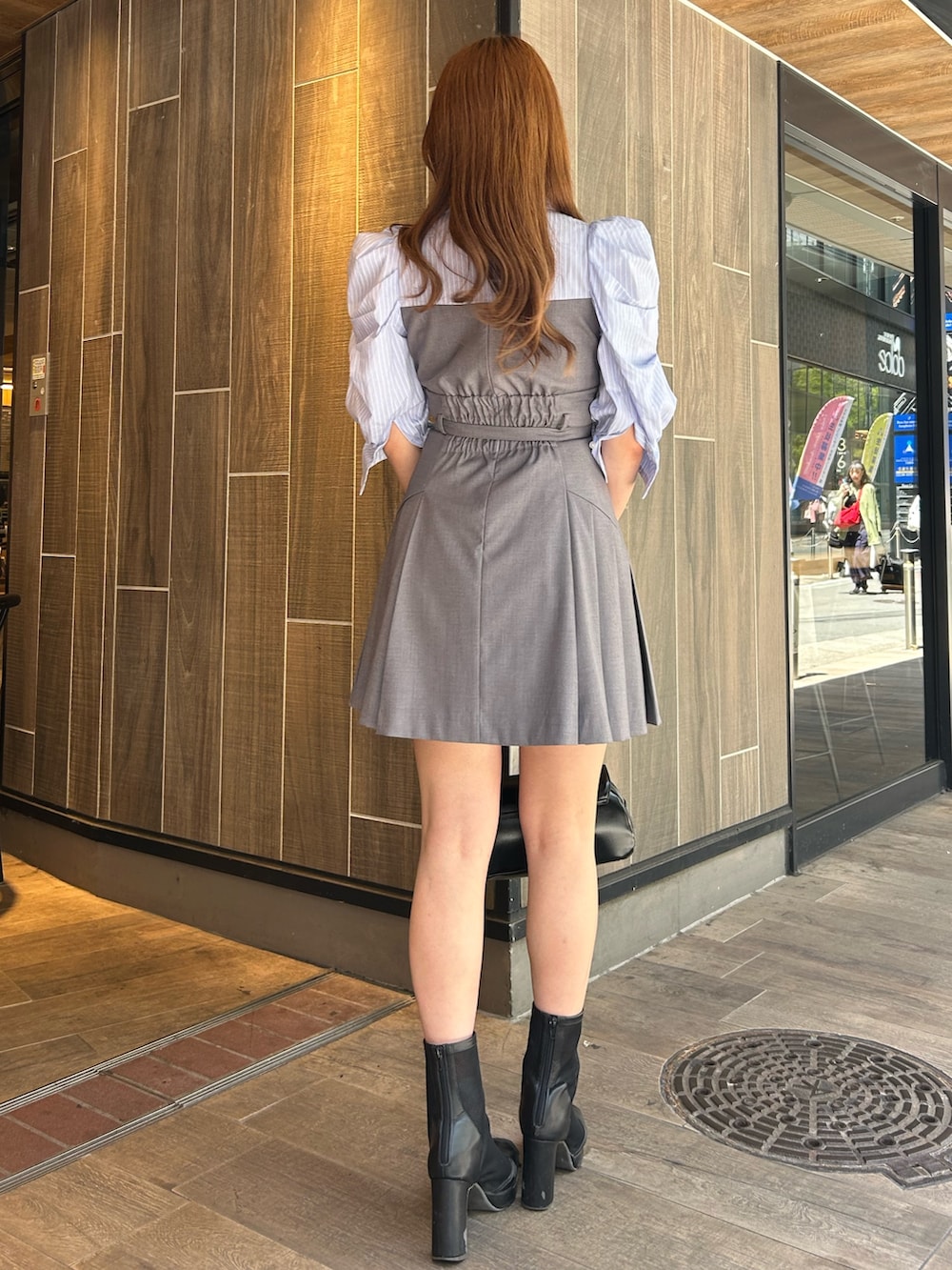 グレー系のワンピース、ブラック系のハンドバッグ、ブラック系のブーツを着用したレディースの春コーディネートの3枚目の写真