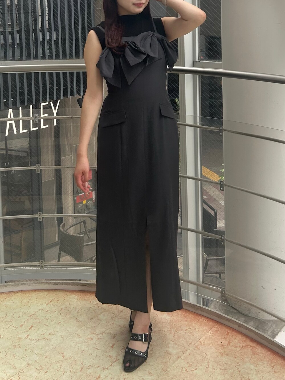 グレー系のワンピース、ブラック系のパンプス、ブラック系のニット/セーターを着用したレディースの夏コーディネートの2枚目の写真