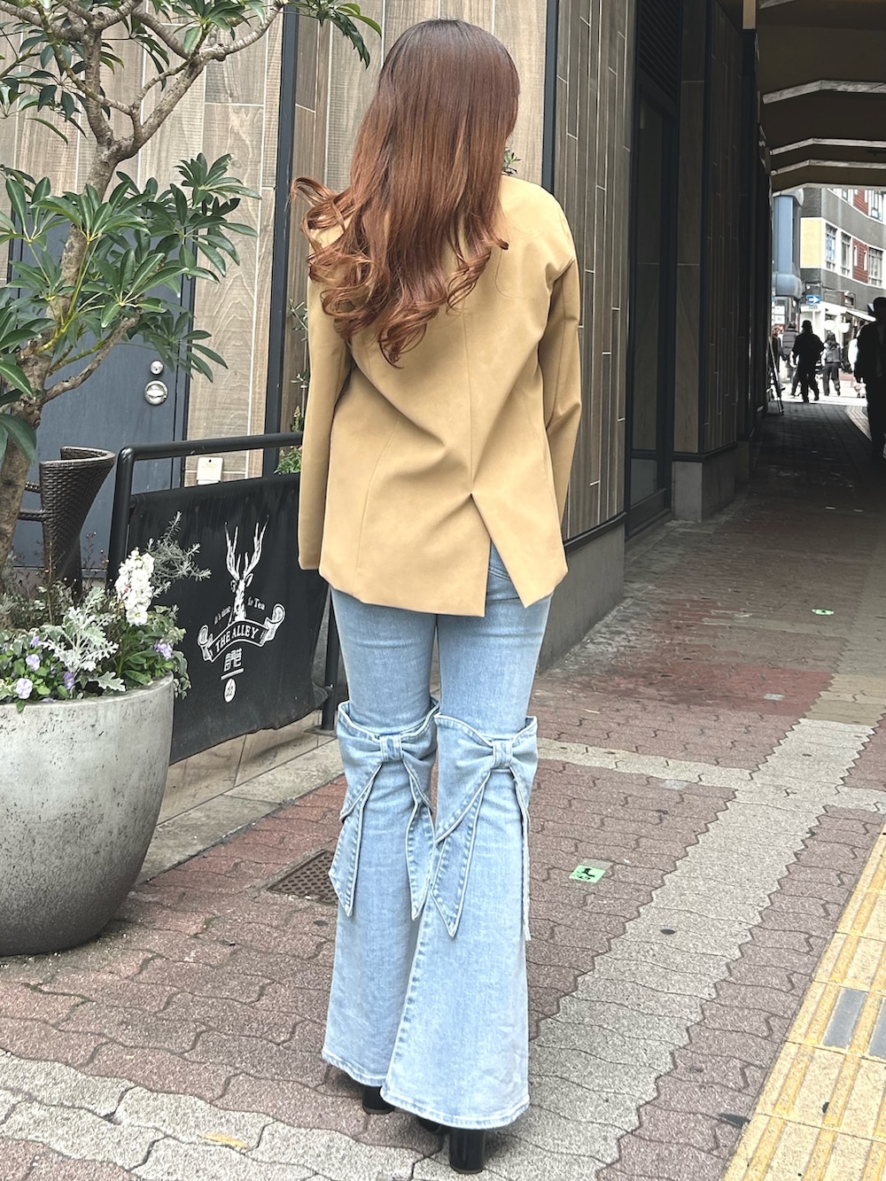 ブルー系のデニムパンツ、ブラウン系のパンプス、ベージュ系のテーラードジャケットを着用したレディースの春コーディネートの4枚目の写真