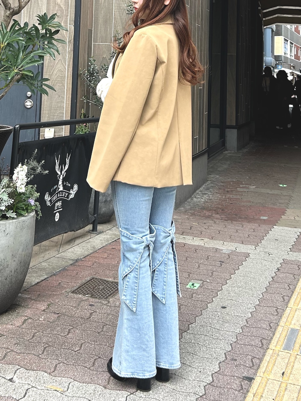 ブルー系のデニムパンツ、ブラウン系のパンプス、ベージュ系のテーラードジャケットを着用したレディースの春コーディネートの3枚目の写真