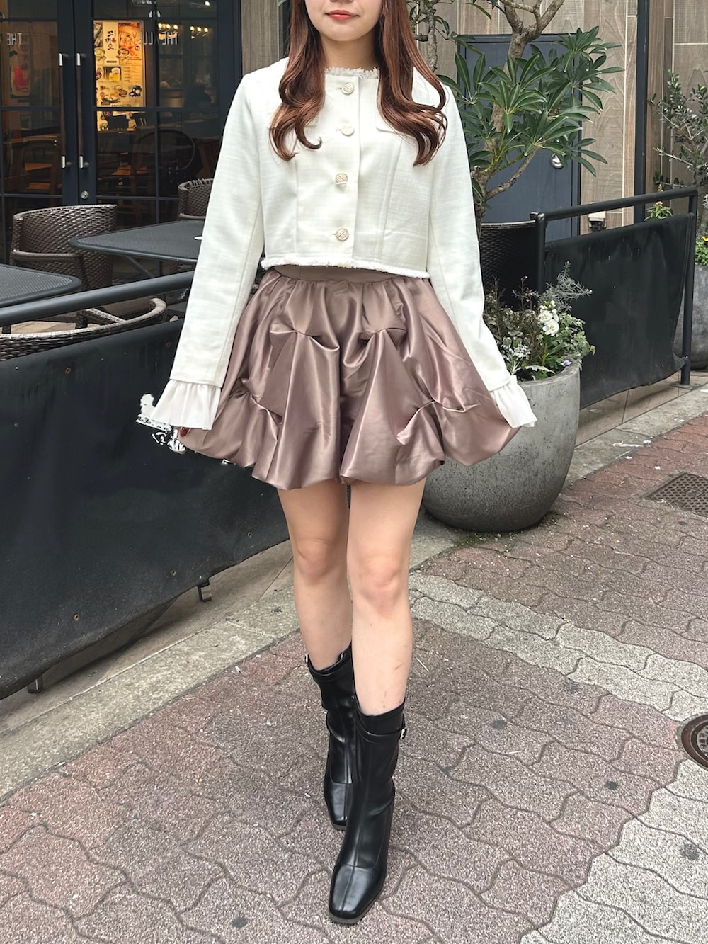 ホワイト系のノーカラージャケット、ブラウン系のスカート、ブラック系のブーツを着用したレディースの冬コーディネートの2枚目の写真