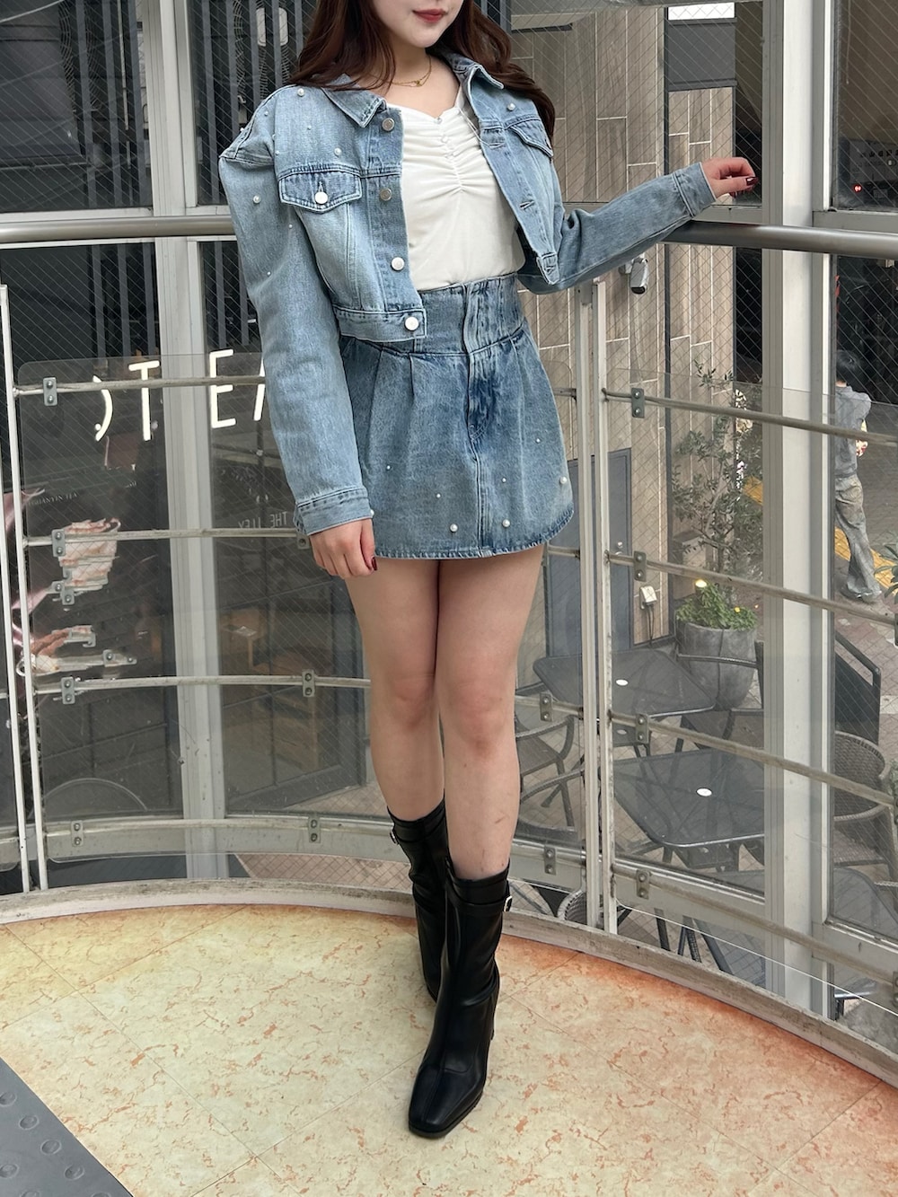 ブルー系のデニムジャケット、ブルー系のデニムパンツ、ブラック系のブーツを着用したレディースの冬コーディネートの2枚目の写真