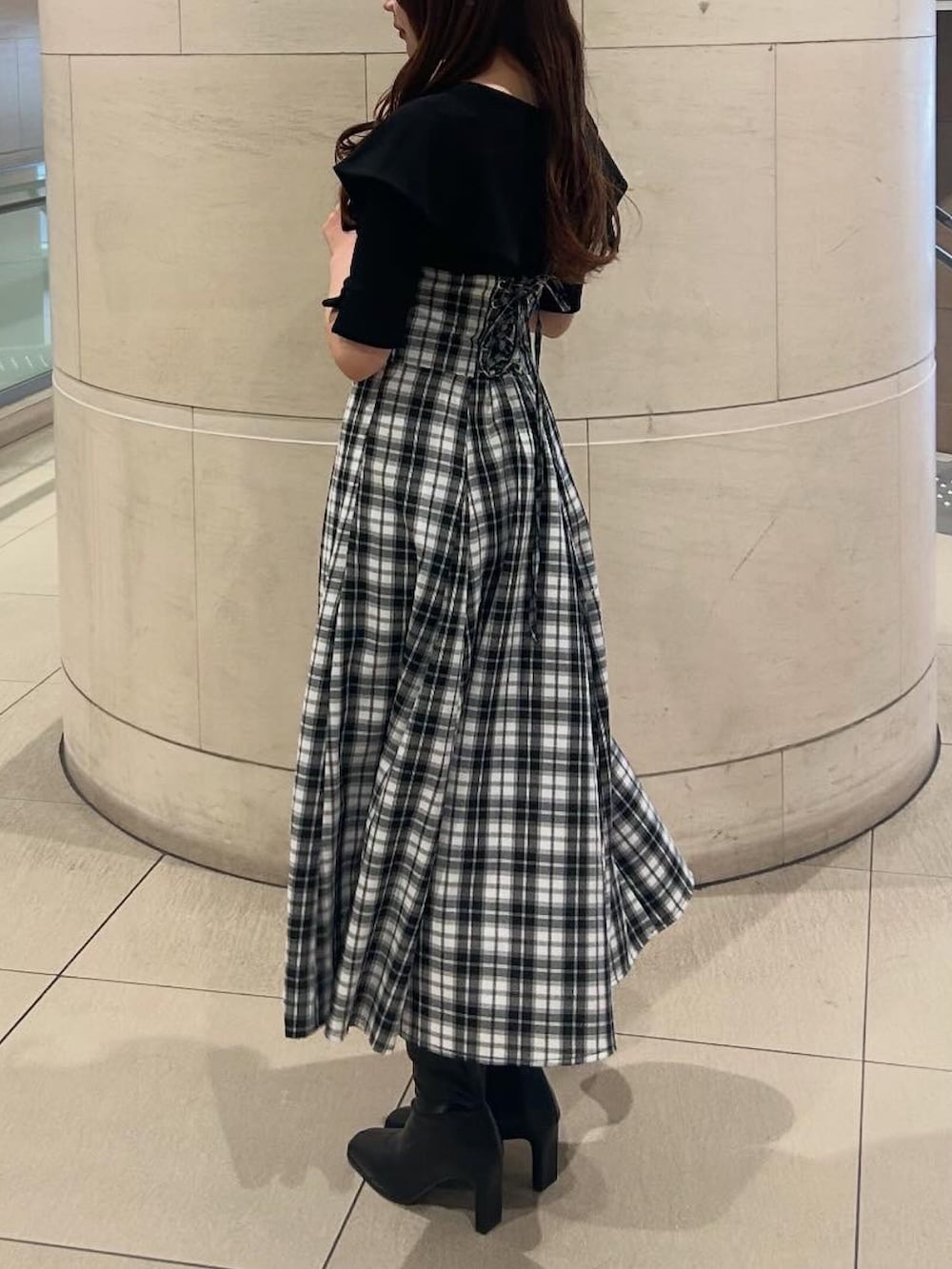 ブラック系のワンピース、ブラック系のブーツを着用したレディースの春コーディネートの3枚目の写真