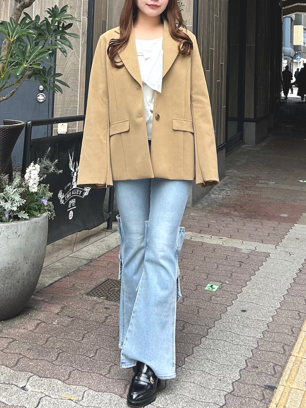 ブルー系のデニムパンツ、ブラウン系のパンプス、ベージュ系のテーラードジャケットを着用したレディースの春コーディネートの2枚目の写真