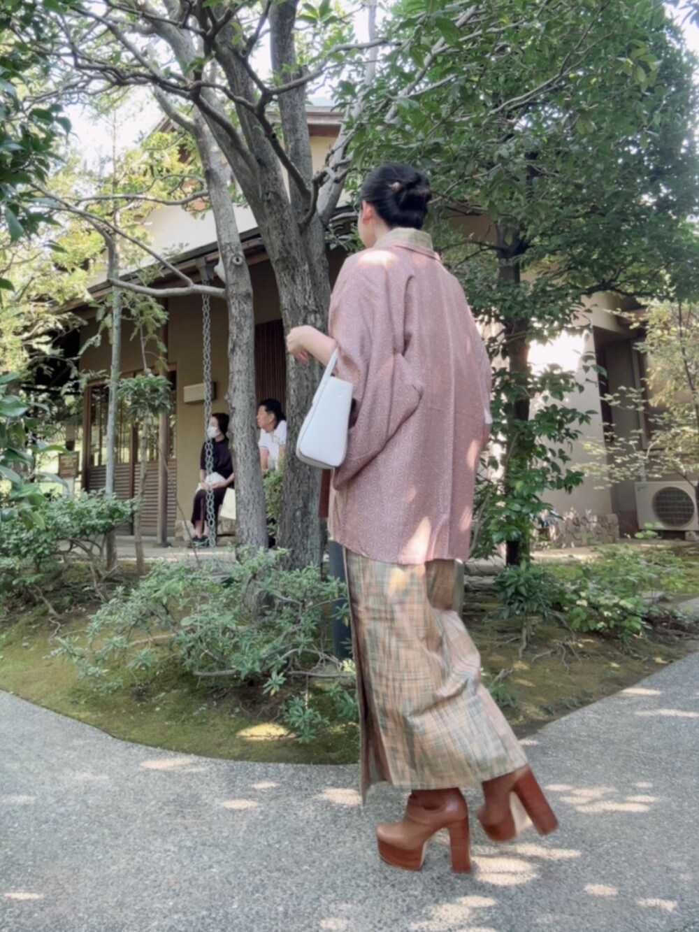 レッド系のハンドバッグ、ブラウン系のブーツを着用したレディースの秋コーディネートの2枚目の写真