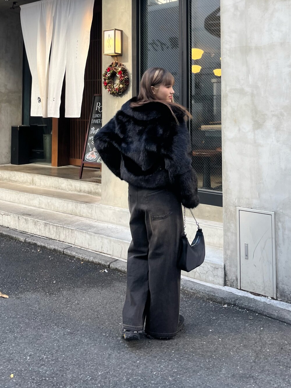 ブラック系のデニムパンツ、ブラック系のニット/セーター、ブラック系のムートンコートを着用したレディースの冬コーディネートの3枚目の写真