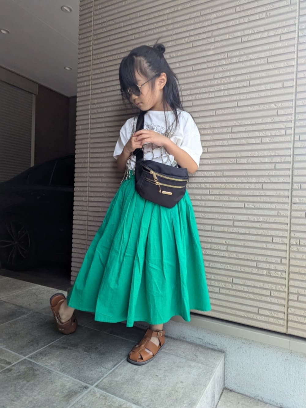 グリーン系のスカート、ホワイト系のTシャツ/カットソー、シルバー系のサスペンダーを着用したキッズの夏コーディネートの2枚目の写真