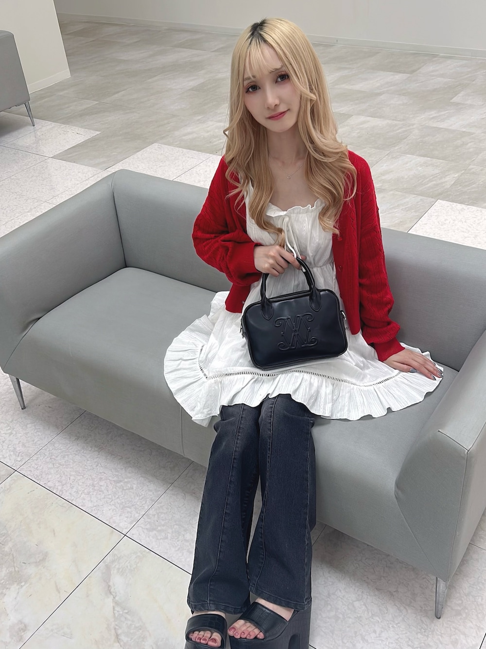ホワイト系のワンピース、レッド系のカーディガン/ボレロ、グレー系のデニムパンツを着用したレディースの春コーディネートの5枚目の写真