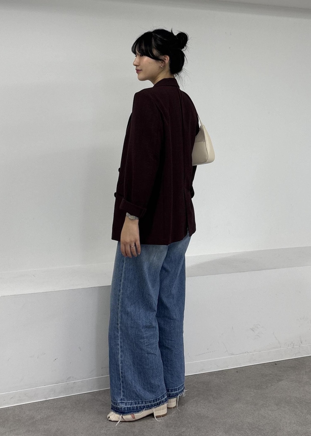 ホワイト系のショルダーバッグ、ブルー系のデニムパンツ、ホワイト系のパンプスを着用したレディースの夏コーディネートの3枚目の写真