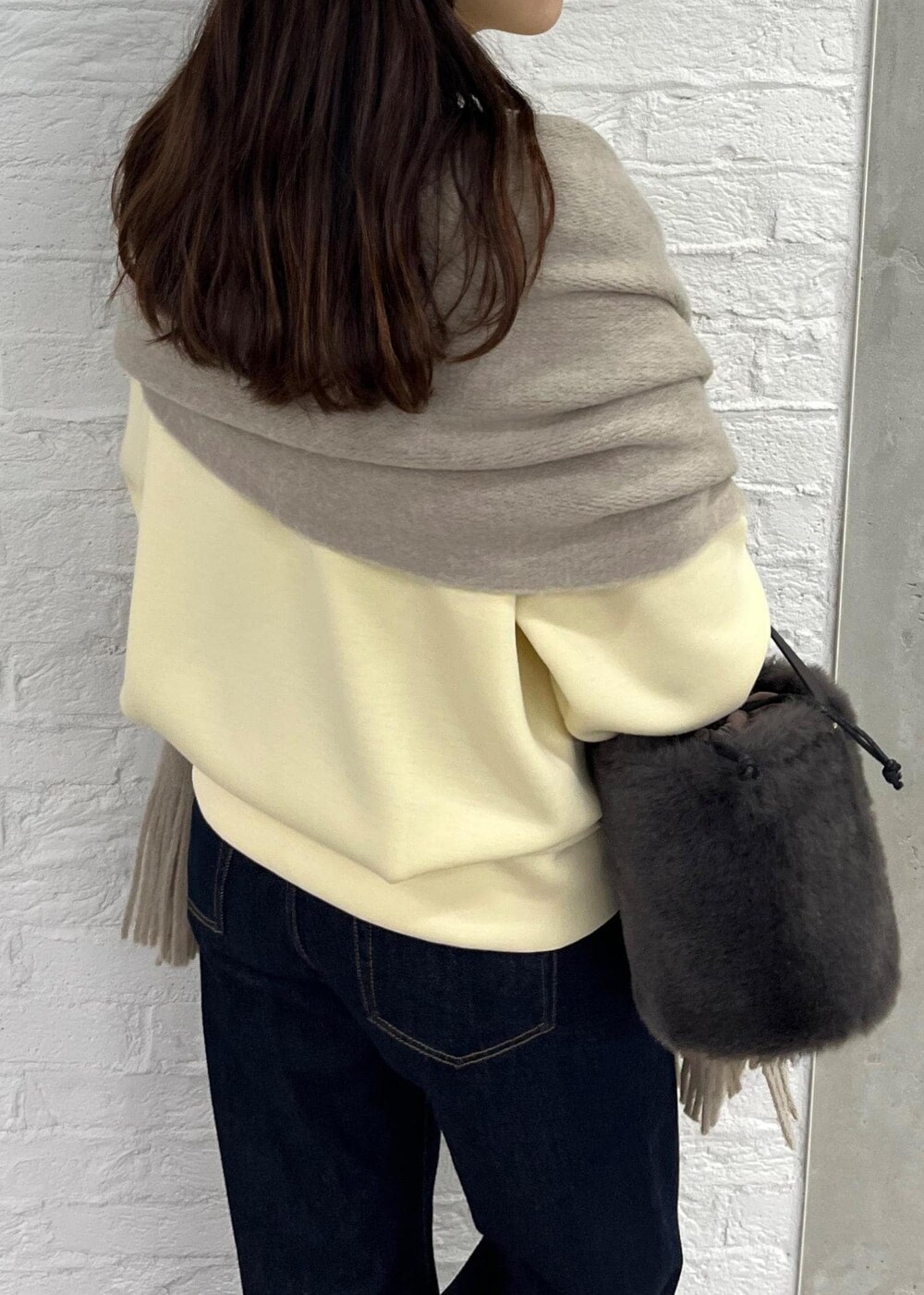 ブルー系のデニムパンツ、グレー系のショルダーバッグ、ベージュ系のその他トップスを着用したレディースの秋コーディネートの6枚目の写真