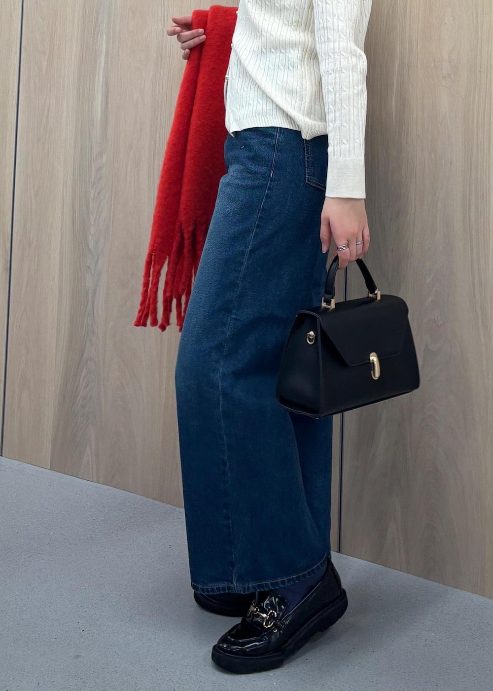 ブルー系のデニムパンツ、ブラック系のハンドバッグ、ホワイト系のカーディガン/ボレロを着用したレディースの冬コーディネートの6枚目の写真