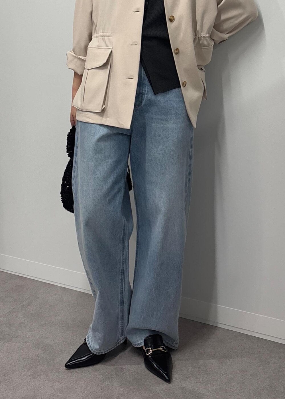 ブルー系のデニムパンツ、ブラック系のパンプス、ホワイト系のミリタリージャケットを着用したレディースの春コーディネートの4枚目の写真