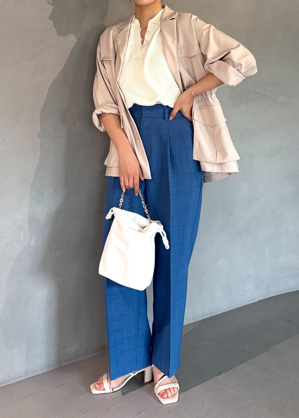 ホワイト系のミリタリージャケット、ブルー系のスラックス、ホワイト系のニット/セーターを着用したレディースの春コーディネートの2枚目の写真