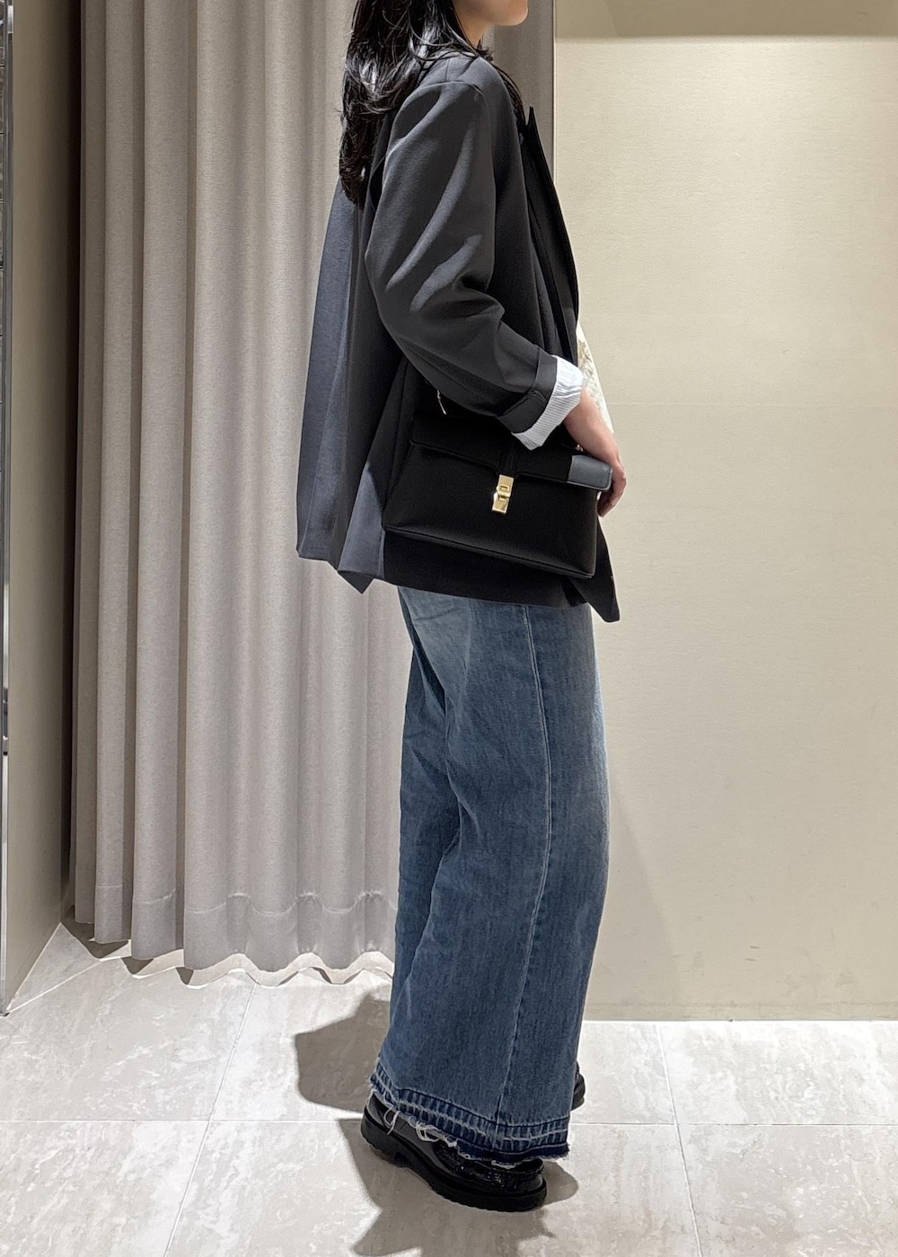 ブラック系のショルダーバッグ、ブルー系のデニムパンツ、ホワイト系のニット/セーターを着用したレディースの春コーディネートの6枚目の写真