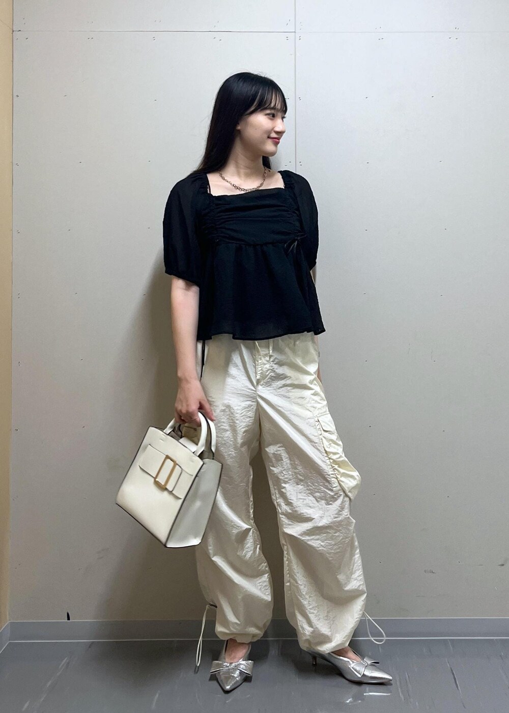 シルバー系のパンプス、ホワイト系のハンドバッグ、ホワイト系のキャミソールを着用したレディースの夏コーディネートの5枚目の写真