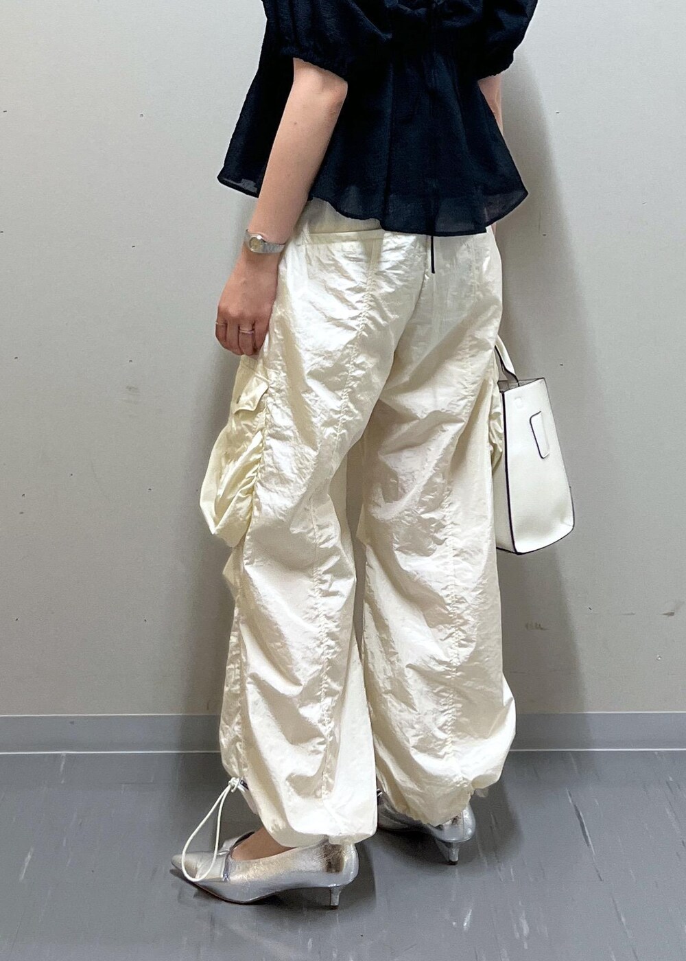 シルバー系のパンプス、ホワイト系のハンドバッグ、ホワイト系のキャミソールを着用したレディースの夏コーディネートの4枚目の写真
