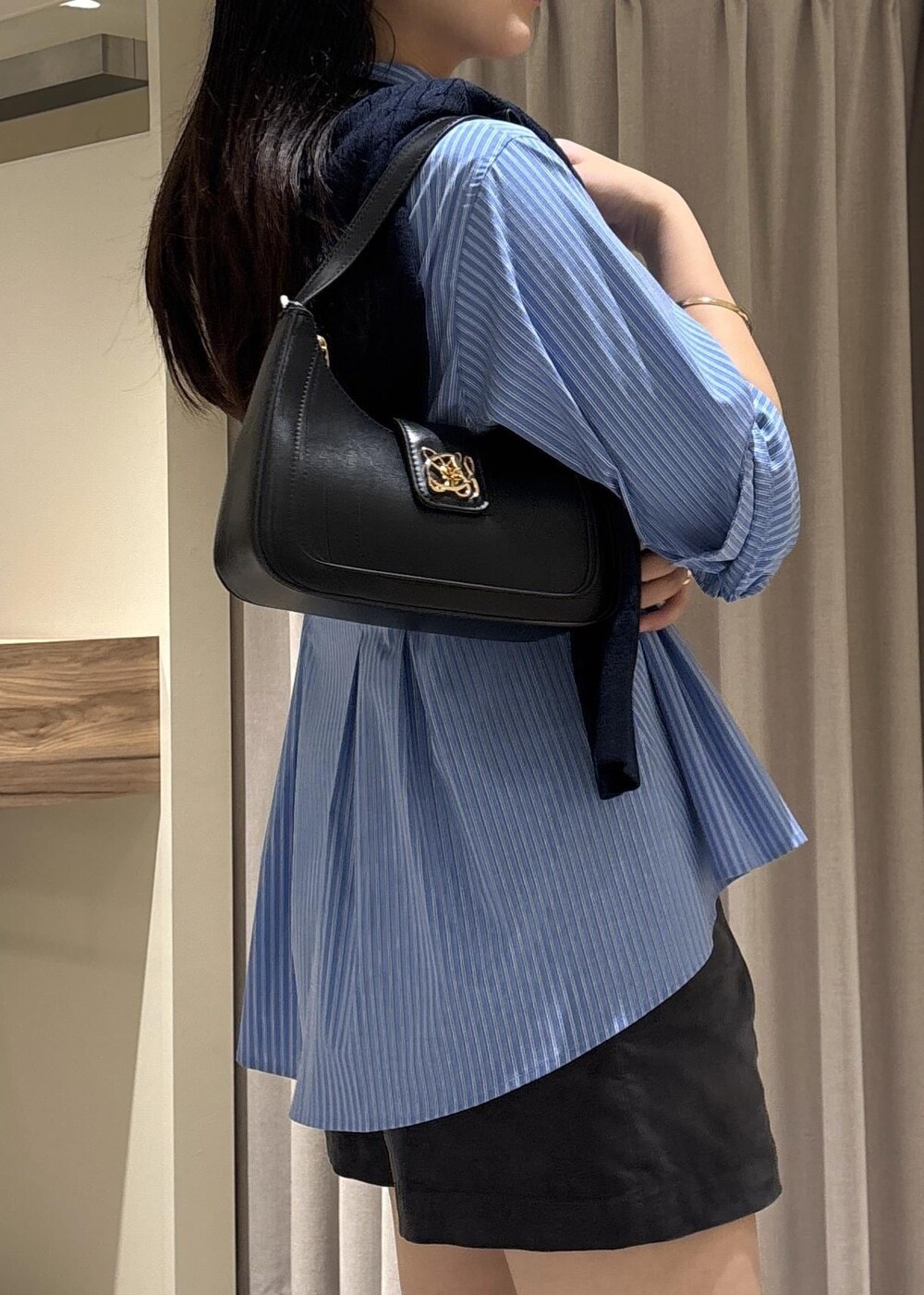 ブラック系のショルダーバッグ、ブラック系のブーツ、グレー系のその他パンツを着用したレディースの秋コーディネートの3枚目の写真