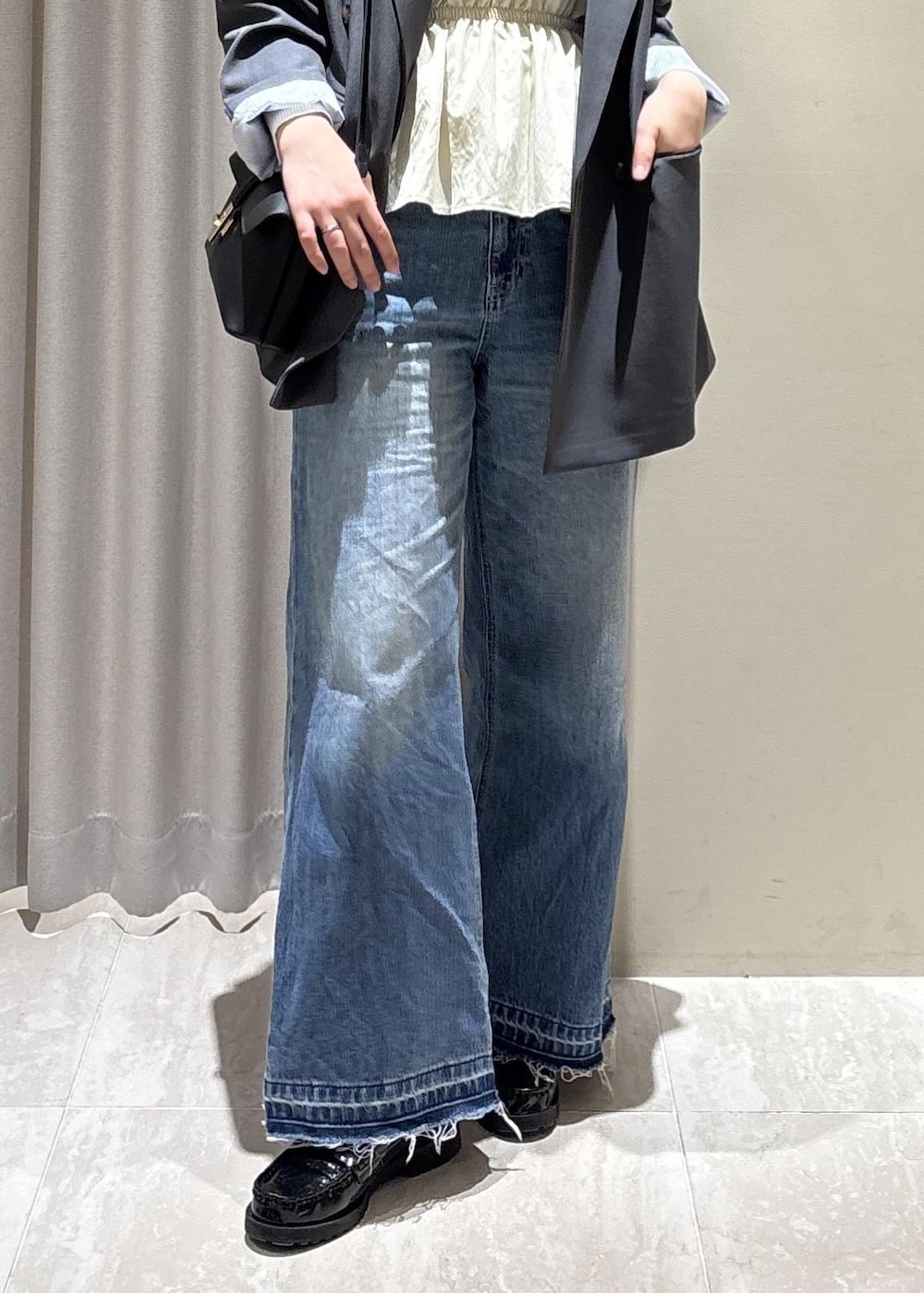 ブラック系のショルダーバッグ、ブルー系のデニムパンツ、ホワイト系のニット/セーターを着用したレディースの春コーディネートの10枚目の写真