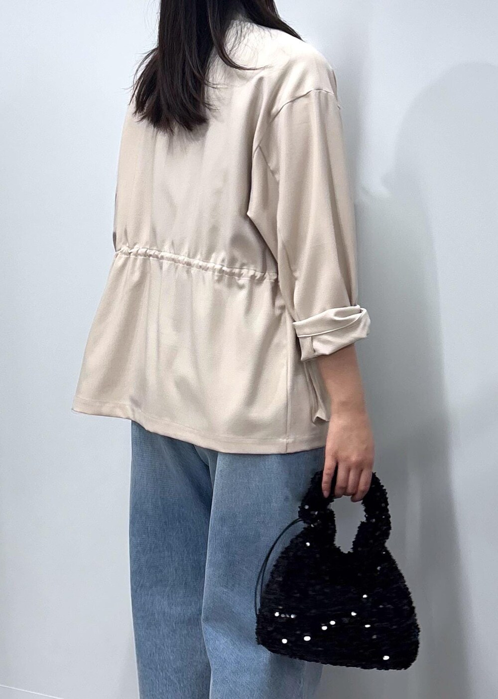 ブルー系のデニムパンツ、ブラック系のパンプス、ホワイト系のミリタリージャケットを着用したレディースの春コーディネートの7枚目の写真