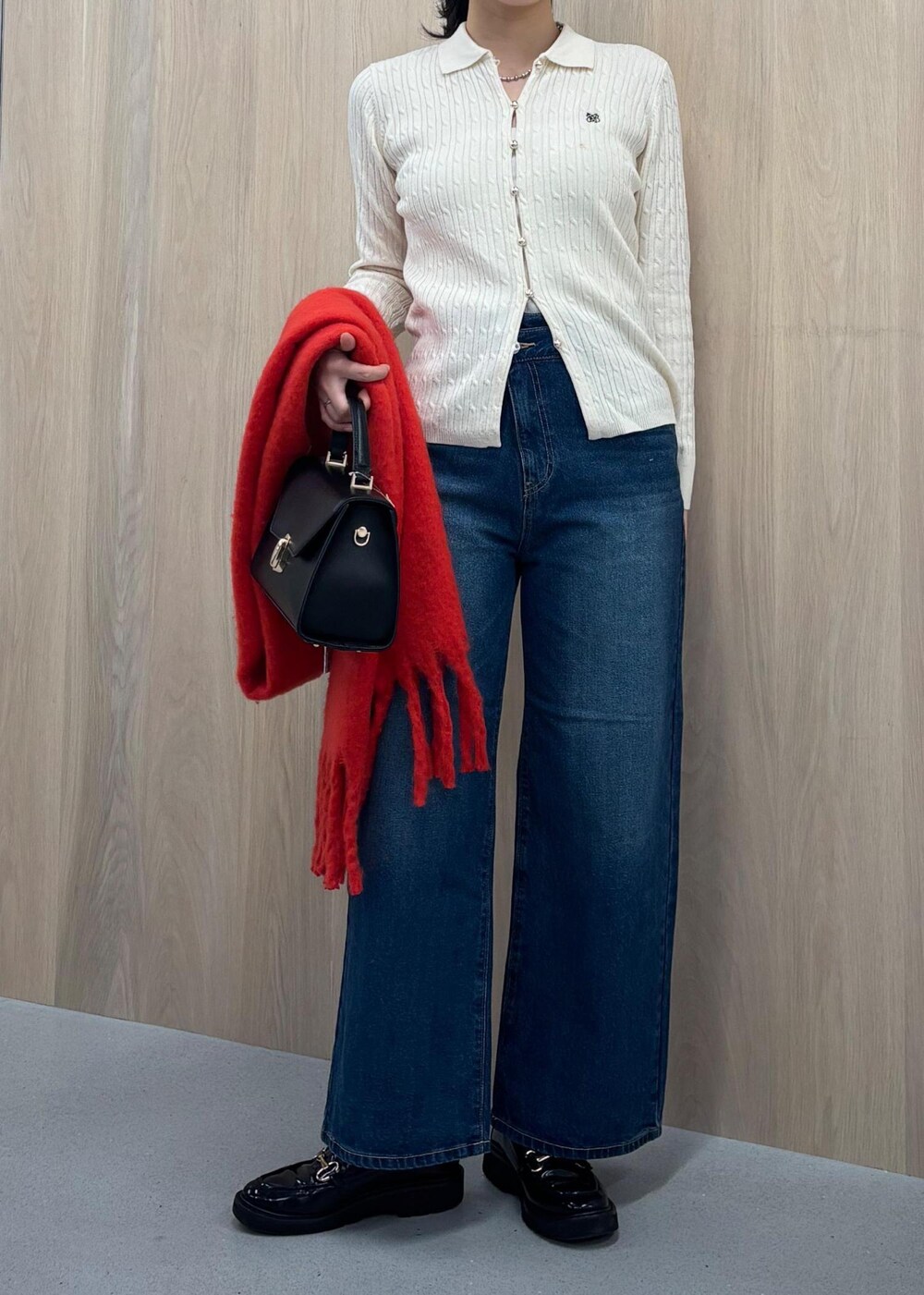 ブルー系のデニムパンツ、ブラック系のハンドバッグ、ホワイト系のカーディガン/ボレロを着用したレディースの冬コーディネートの3枚目の写真