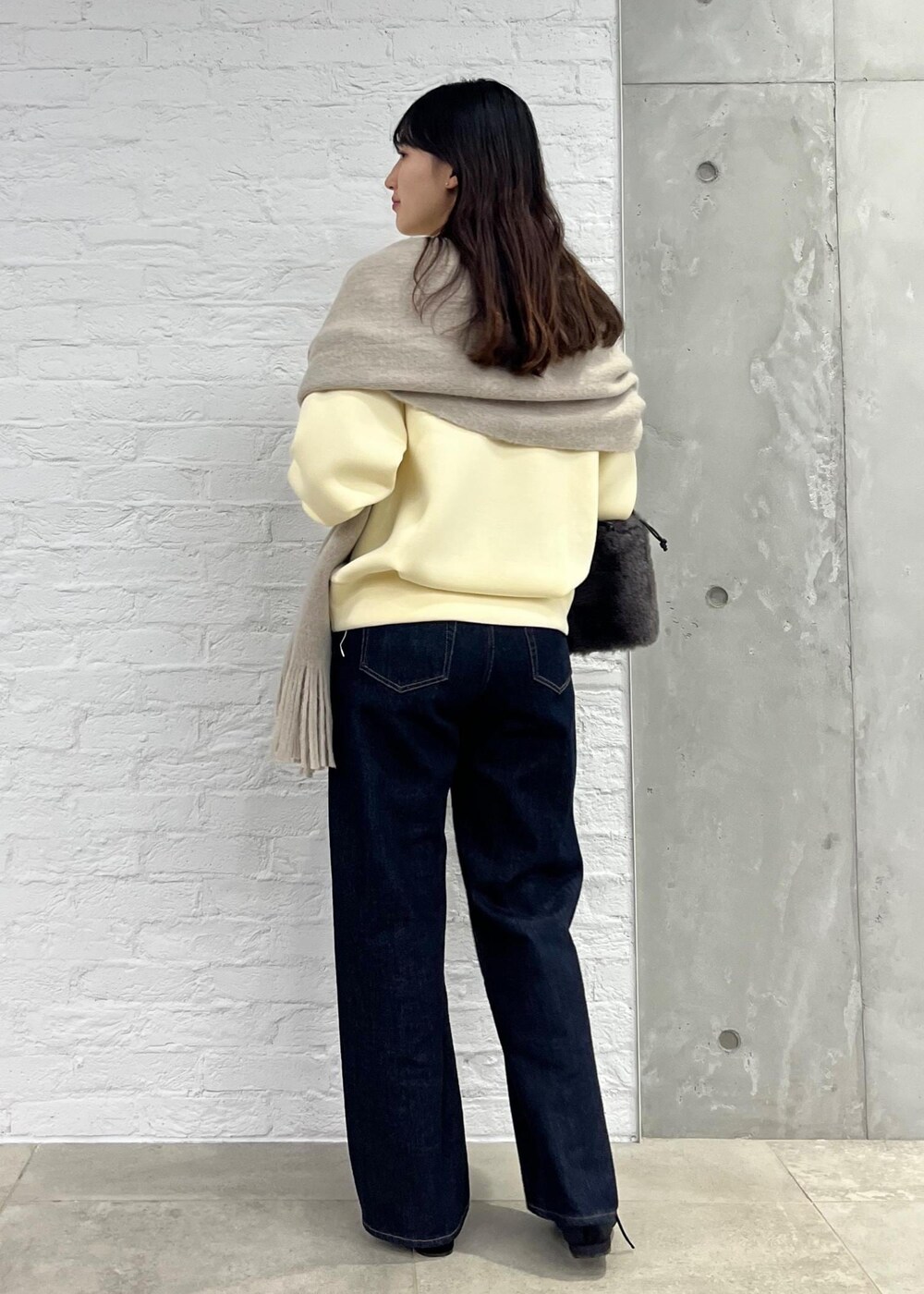 ブルー系のデニムパンツ、グレー系のショルダーバッグ、ベージュ系のその他トップスを着用したレディースの秋コーディネートの3枚目の写真