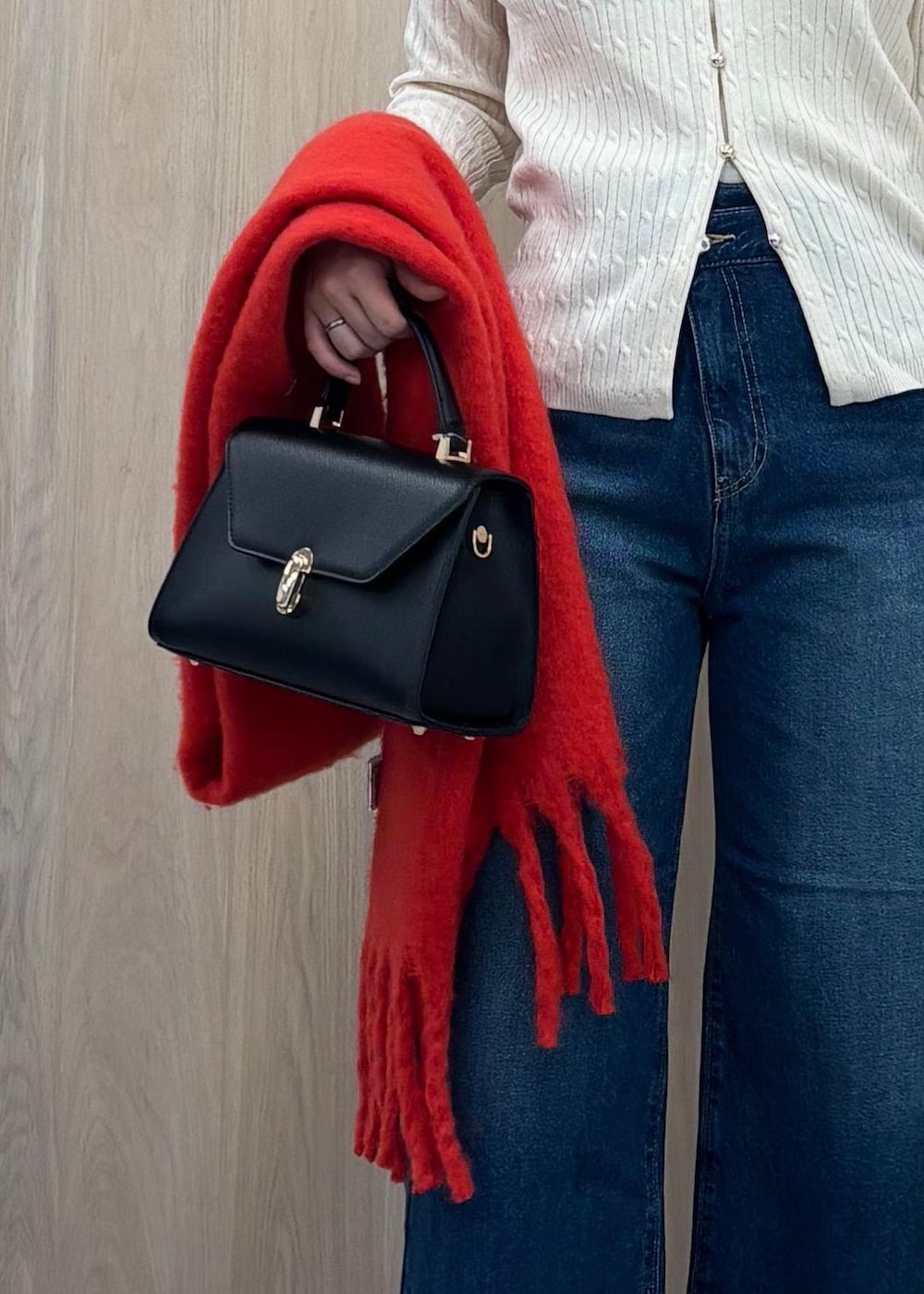 ブルー系のデニムパンツ、ブラック系のハンドバッグ、ホワイト系のカーディガン/ボレロを着用したレディースの冬コーディネートの9枚目の写真