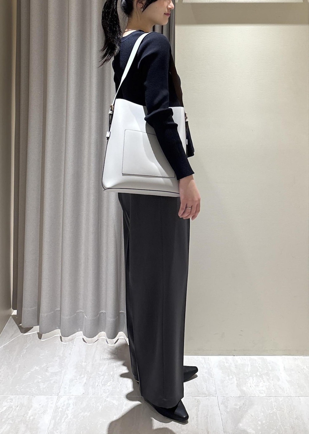 グレー系のトートバッグ、ブラック系のパンプス、ブルー系のカーディガン/ボレロを着用したレディースの春コーディネートの2枚目の写真