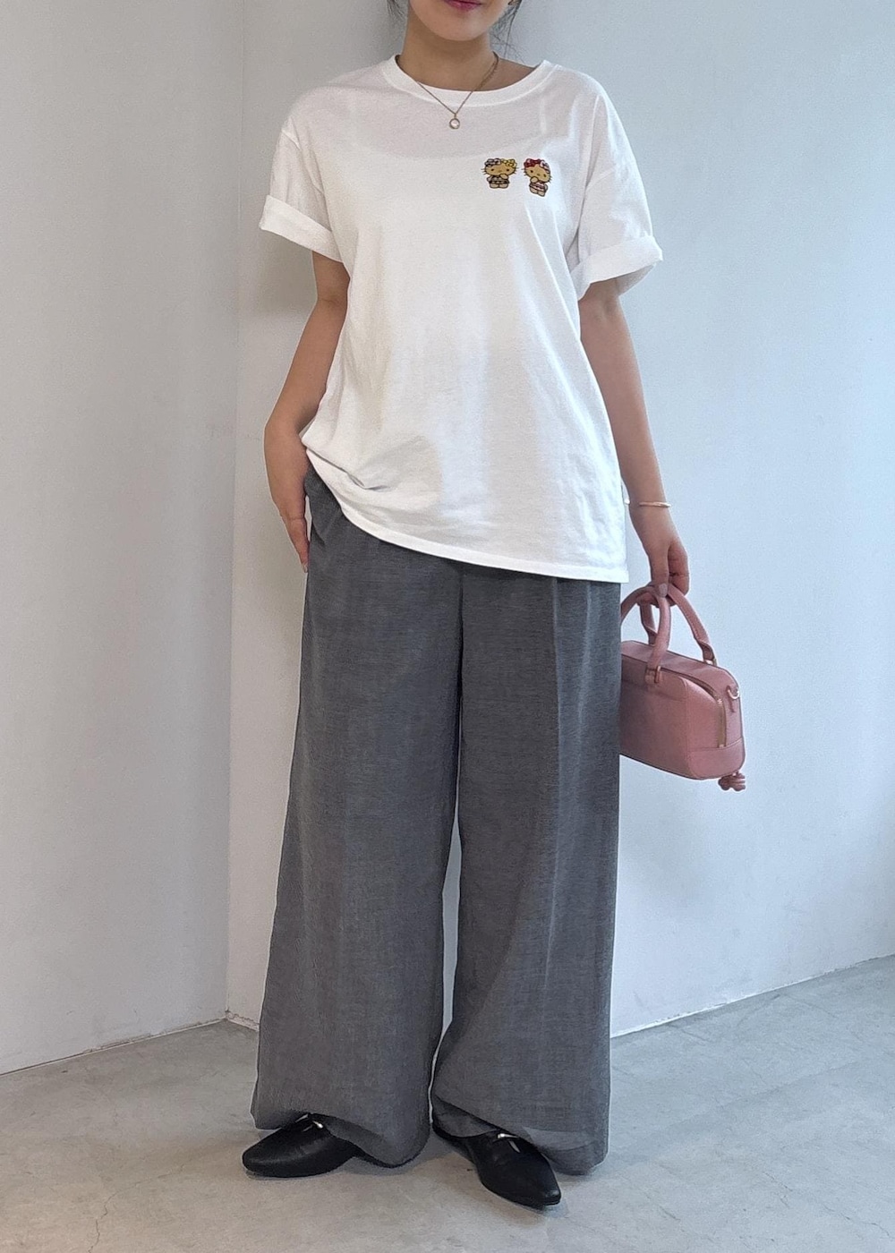 ピンク系のボストンバッグ、ブラック系のパンプス、ホワイト系のTシャツ/カットソーを着用したレディースの夏コーディネートの4枚目の写真