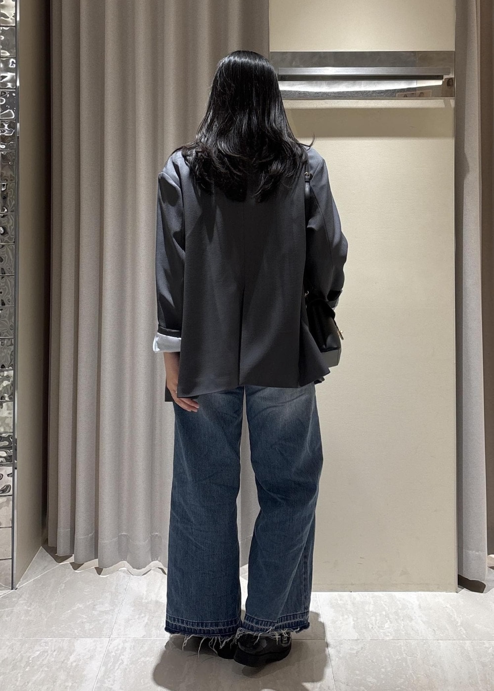 ブラック系のショルダーバッグ、ブルー系のデニムパンツ、ホワイト系のニット/セーターを着用したレディースの春コーディネートの5枚目の写真