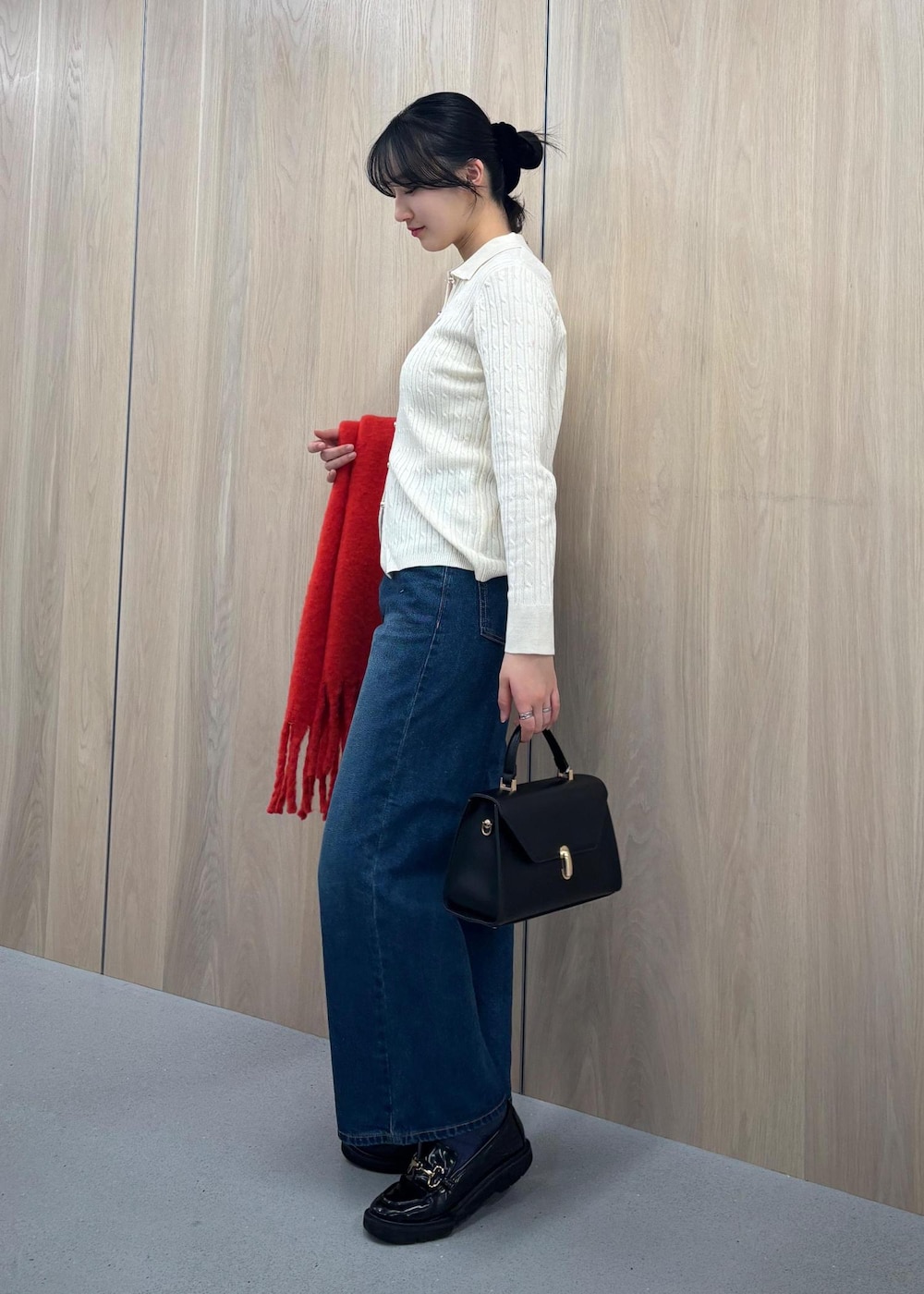 ブルー系のデニムパンツ、ブラック系のハンドバッグ、ホワイト系のカーディガン/ボレロを着用したレディースの冬コーディネートの2枚目の写真