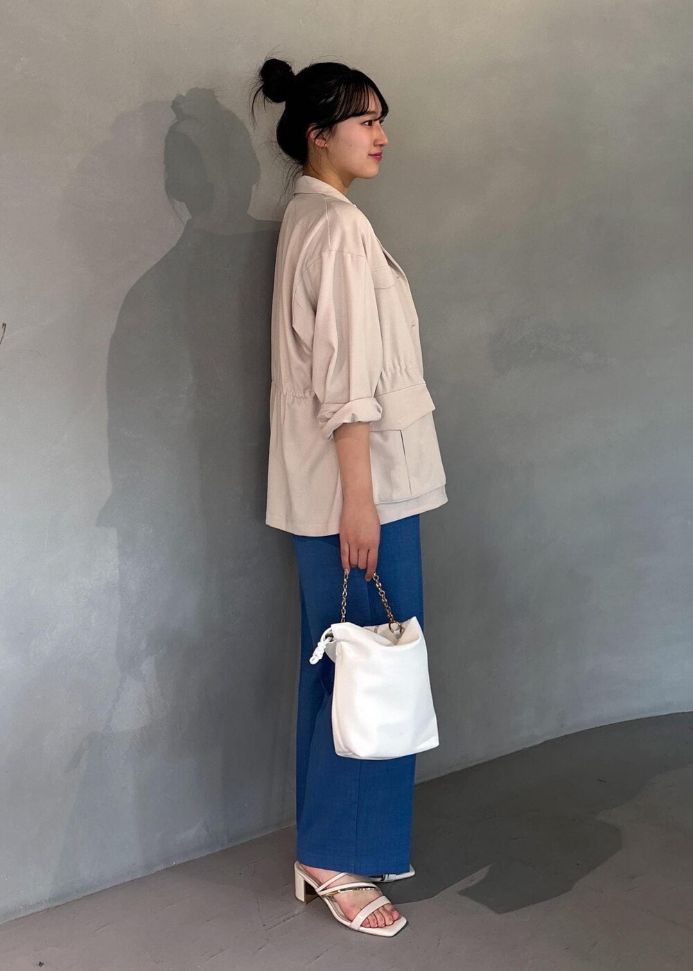 ホワイト系のミリタリージャケット、ブルー系のスラックス、ホワイト系のニット/セーターを着用したレディースの春コーディネートの6枚目の写真