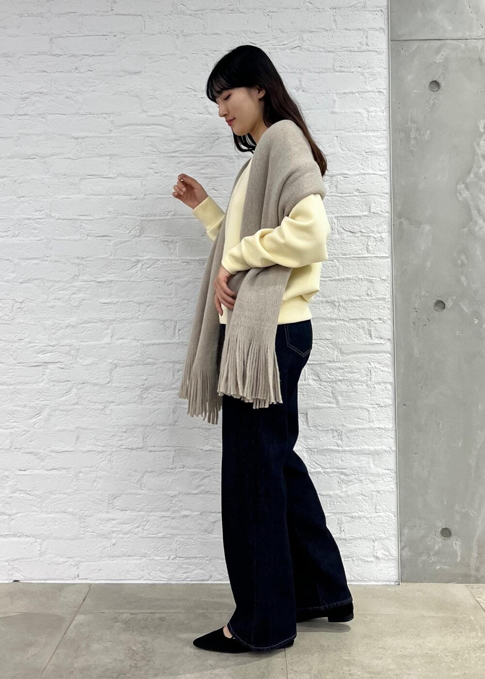 ブルー系のデニムパンツ、グレー系のショルダーバッグ、ベージュ系のその他トップスを着用したレディースの秋コーディネートの2枚目の写真