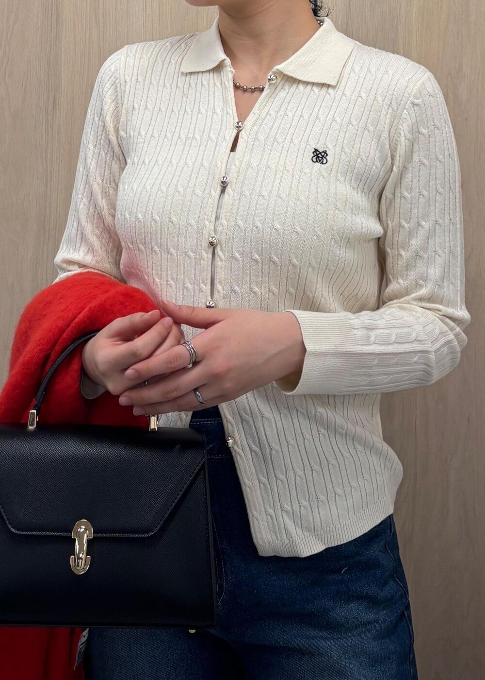 ブルー系のデニムパンツ、ブラック系のハンドバッグ、ホワイト系のカーディガン/ボレロを着用したレディースの冬コーディネートの4枚目の写真