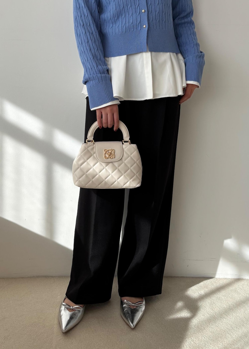 ブルー系のカーディガン/ボレロ、ホワイト系のシャツ/ブラウス、ブルー系のスラックスを着用したレディースの冬コーディネートの4枚目の写真