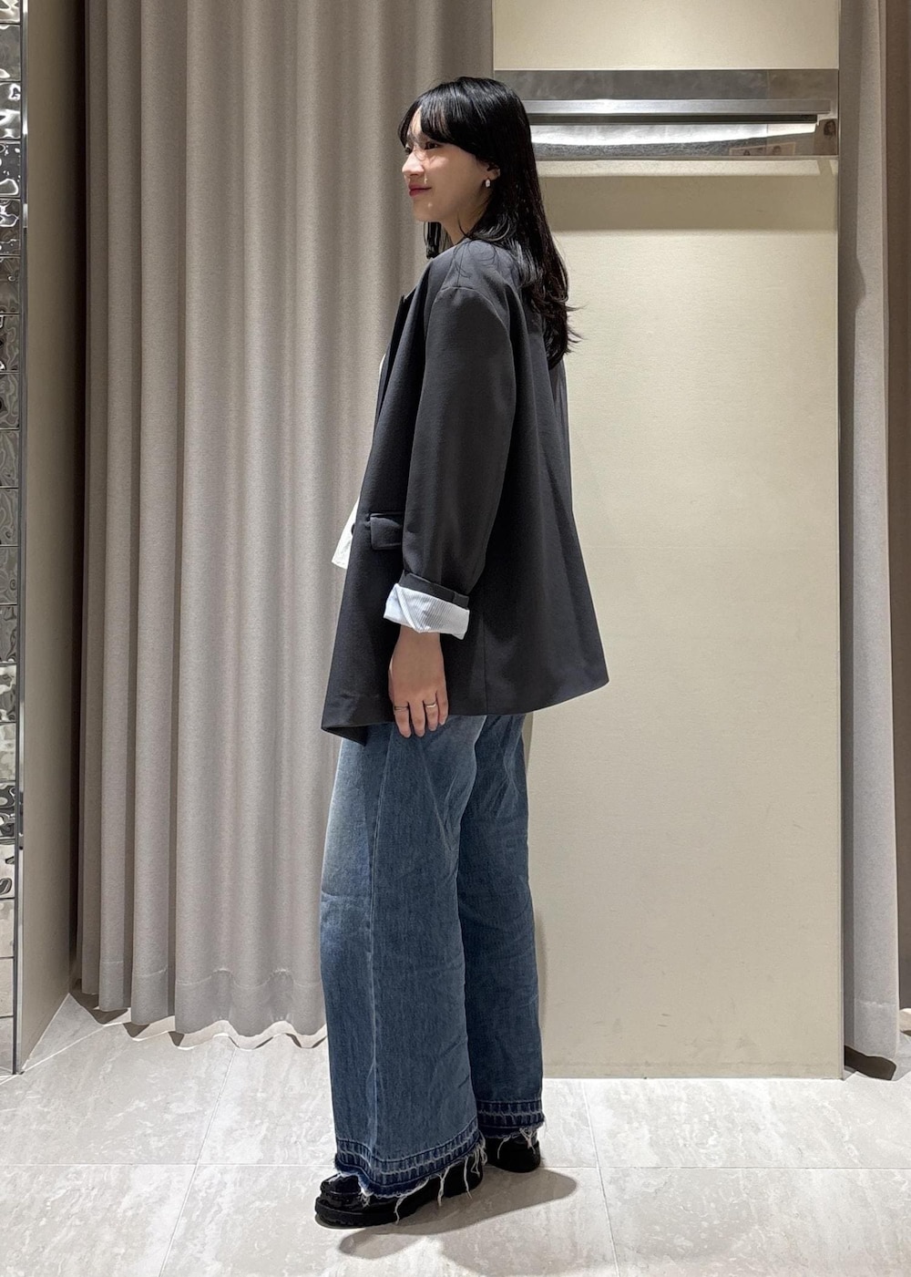 ブラック系のショルダーバッグ、ブルー系のデニムパンツ、ホワイト系のニット/セーターを着用したレディースの春コーディネートの4枚目の写真