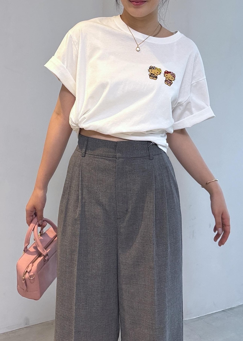 ピンク系のボストンバッグ、ブラック系のパンプス、ホワイト系のTシャツ/カットソーを着用したレディースの夏コーディネートの6枚目の写真