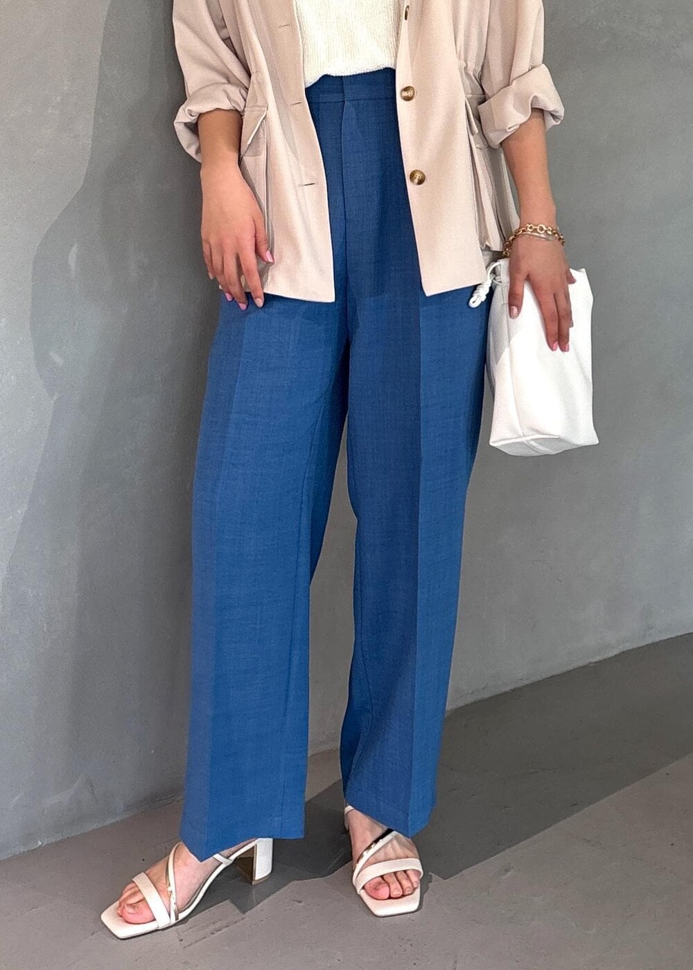 ホワイト系のミリタリージャケット、ブルー系のスラックス、ホワイト系のニット/セーターを着用したレディースの春コーディネートの4枚目の写真