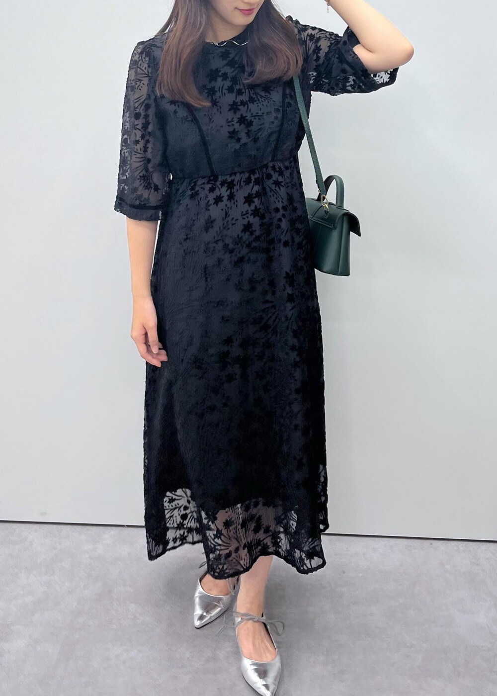 シルバー系のパンプス、グリーン系のショルダーバッグ、ブラック系のドレスを着用したレディースの秋コーディネートの6枚目の写真