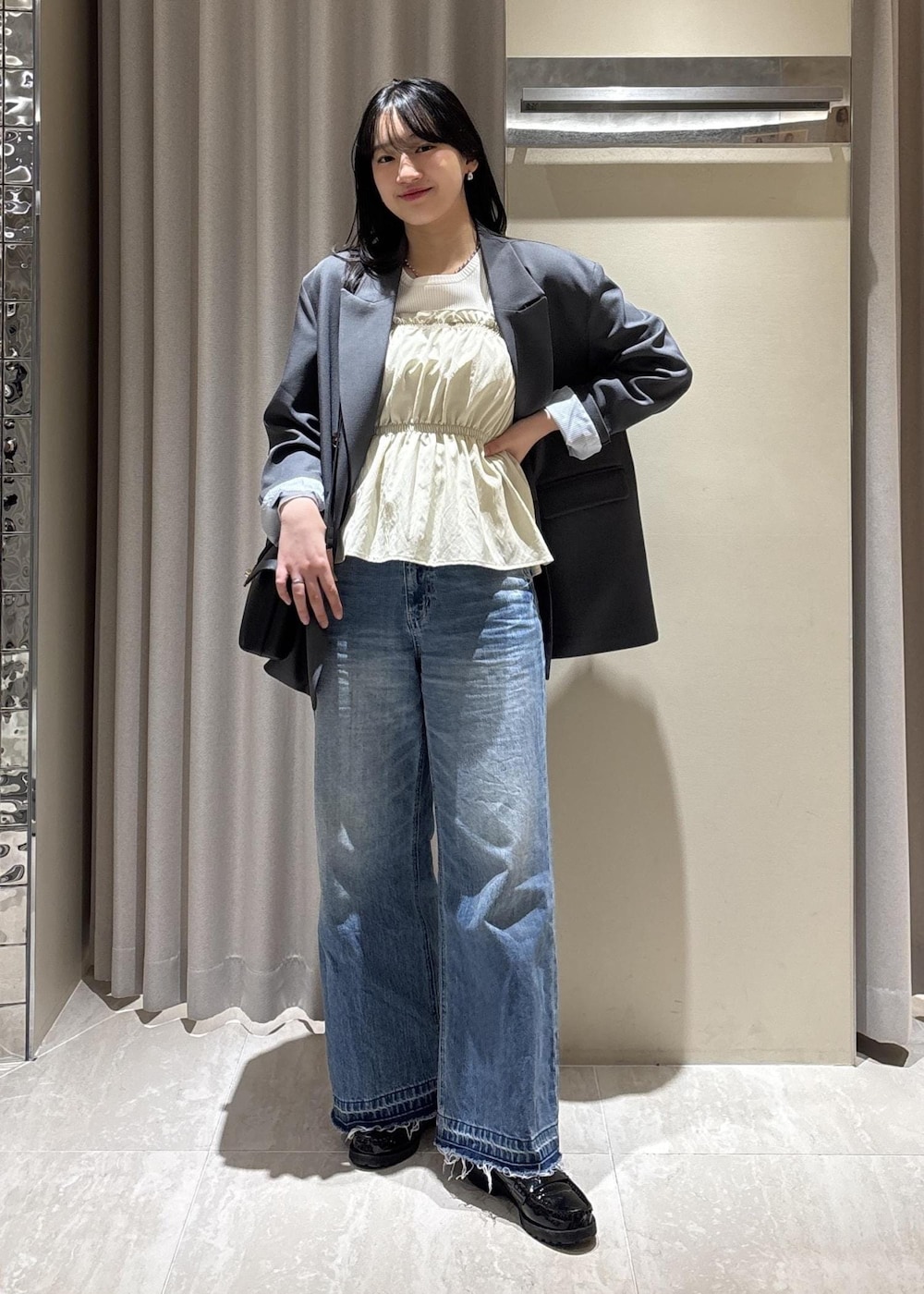 ブラック系のショルダーバッグ、ブルー系のデニムパンツ、ホワイト系のニット/セーターを着用したレディースの春コーディネートの3枚目の写真