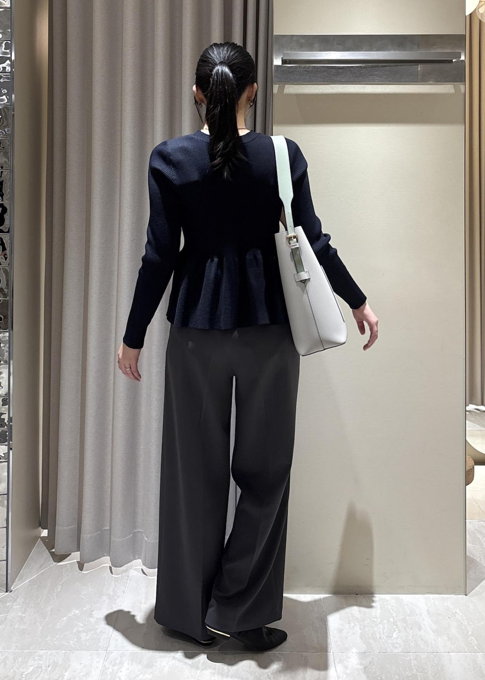 グレー系のトートバッグ、ブラック系のパンプス、ブルー系のカーディガン/ボレロを着用したレディースの春コーディネートの3枚目の写真