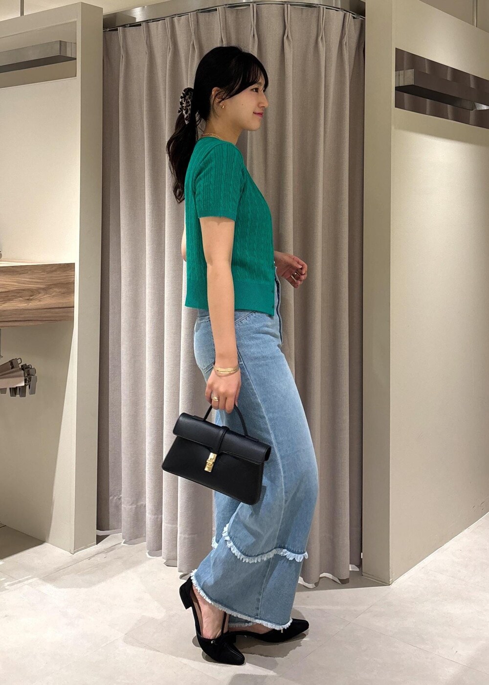 ブラック系のショルダーバッグ、グリーン系のカーディガン/ボレロ、ブルー系のデニムパンツを着用したレディースの秋コーディネートの7枚目の写真