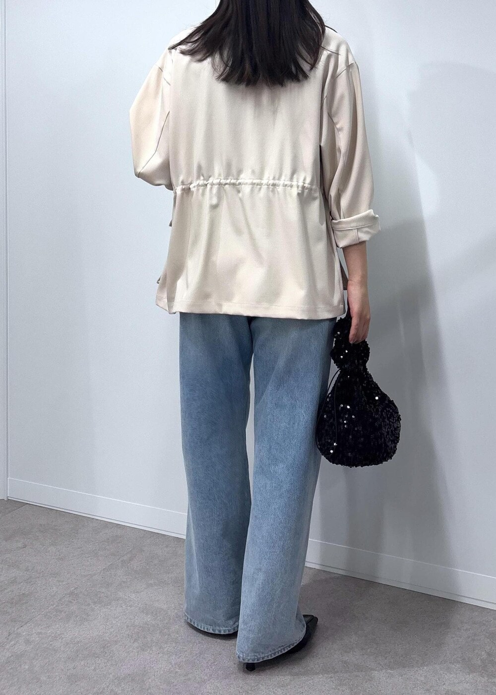 ブルー系のデニムパンツ、ブラック系のパンプス、ホワイト系のミリタリージャケットを着用したレディースの春コーディネートの6枚目の写真