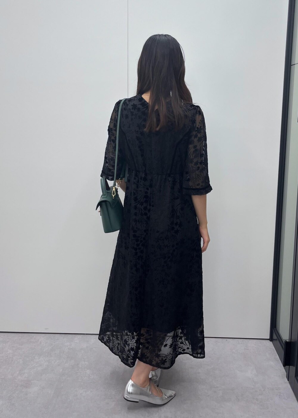 シルバー系のパンプス、グリーン系のショルダーバッグ、ブラック系のドレスを着用したレディースの秋コーディネートの3枚目の写真